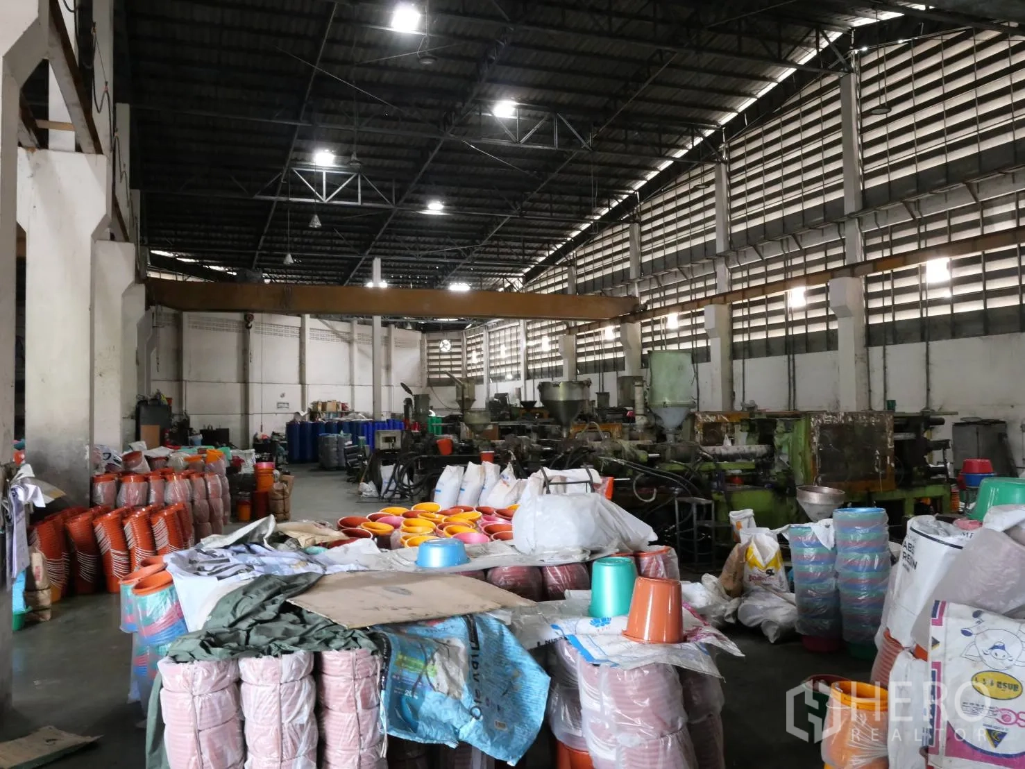 Factory for rent or sale in Bang Khun Thian, Bangkok - Factory aisle filled with machinery and stacked plastic bins and bags.