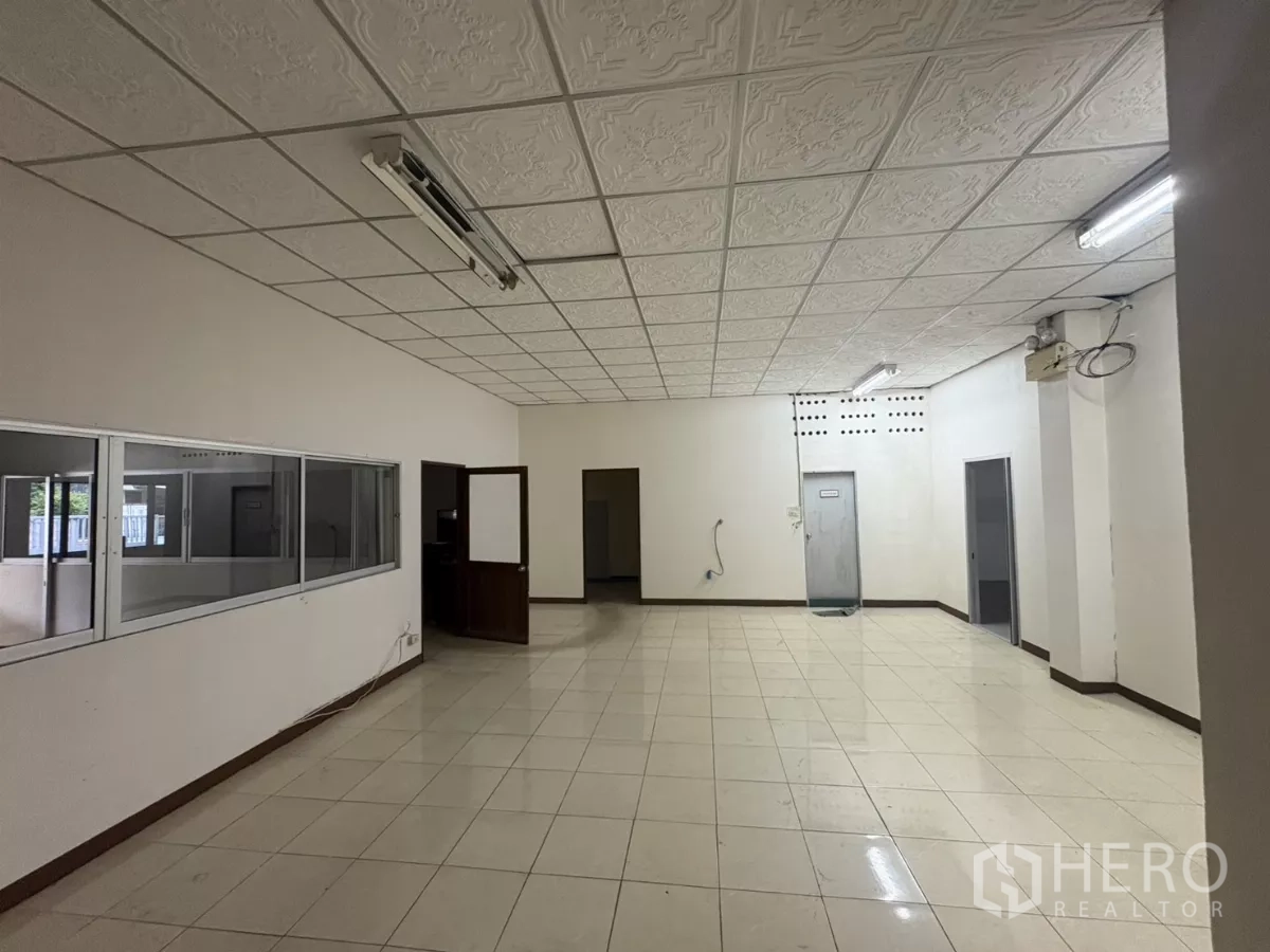 Warehouse for rent in Bang Phli, Samut Prakan - Large tiled office room with glass partition windows.