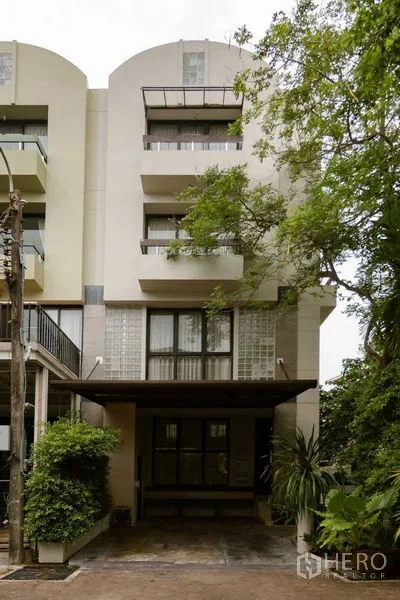 带办公室的家 出售在Watthana, Bangkok - 现代联排外立面，设阳台、雨棚车位与绿化。