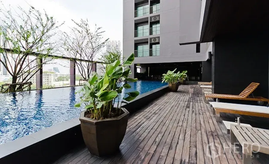 Condominium for rent in Khlong Toei, Bangkok - Elevated condominium swimming pool with wooden sun deck, planters and city skyline views.