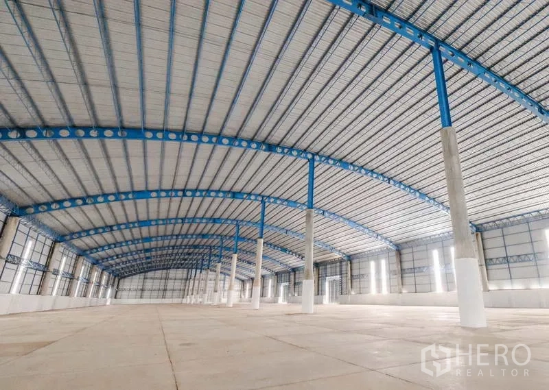 Warehouse for rent in Ban Pho, Chachoengsao - Open storage hall with ventilated metal roofing, concrete flooring, and bright sidewall panels.