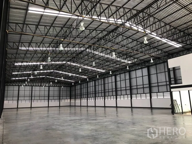 Warehouse for rent in Bang Phli, Samut Prakan - Large column-free warehouse space with metal roof panels and rows of high-bay lights.