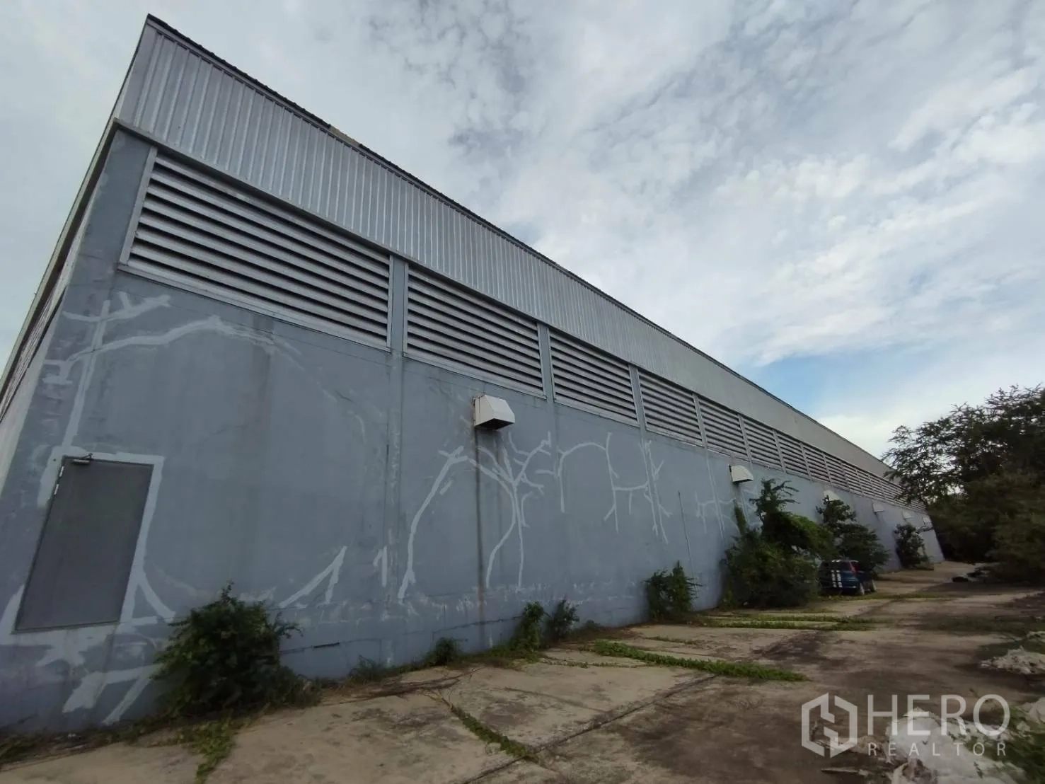 Factory for rent in Samut Prakan - Side elevation of the industrial building with ventilation louvers and service lane.