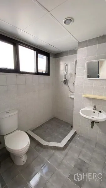 Townhouse for rent in Bang Na, Bangkok - Bathroom with window, corner shower zone, toilet and small basin.