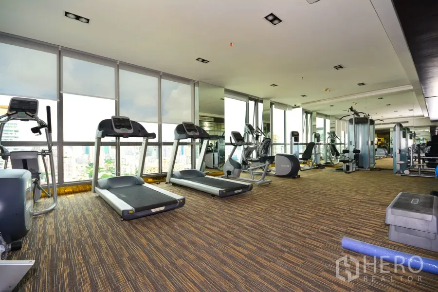Condominium for rent or sale in Watthana, Bangkok - Skyline-view fitness center with treadmills, bikes, and weight machines in a high-rise condo.