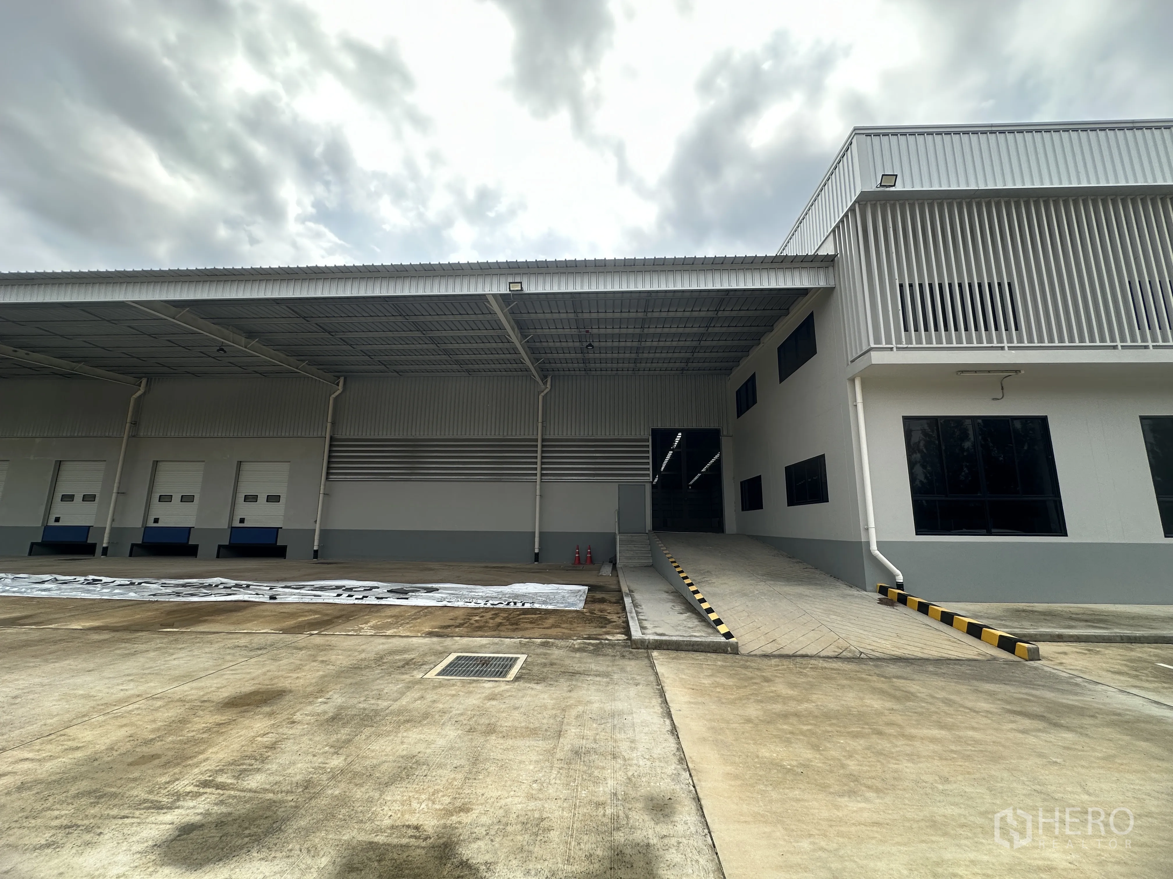 Warehouse for rent in Mueang Chon Buri, Chon Buri - Covered loading platform outside with a vehicle ramp to the warehouse door.