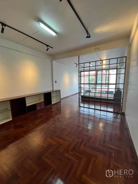 Home Office for rent in Khlong Toei, Bangkok - Polished parquet room with built-in shelving and metal grid partition.