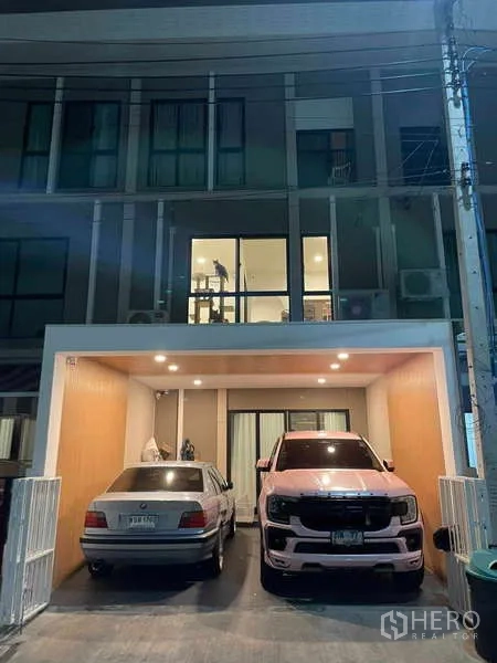 Townhouse for rent or sale in Bang Kapi, Bangkok - Townhouse exterior at night with covered two-car carport and upper windows.