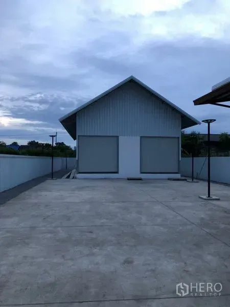 货栈 出租在Bueng Kum, Bangkok - 山墙屋顶仓库，双卷闸门与宽阔混凝土院坪，傍晚景