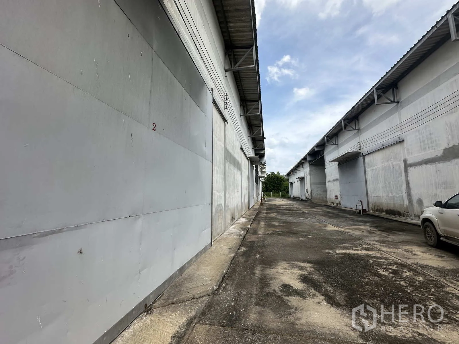 Warehouse for rent in Phra Nakhon Si Ayutthaya - Close-up of warehouse bay with gray sliding door along concrete lane.