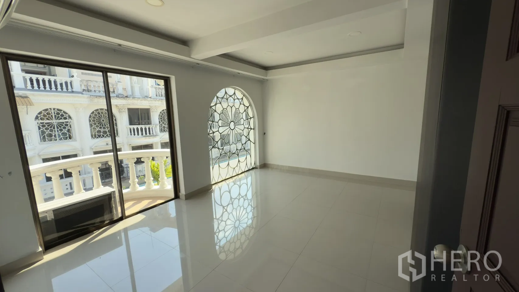 Townhouse for rent in Watthana, Bangkok - Bedroom with an arched decorative window grille and sliding door to a curved balcony.