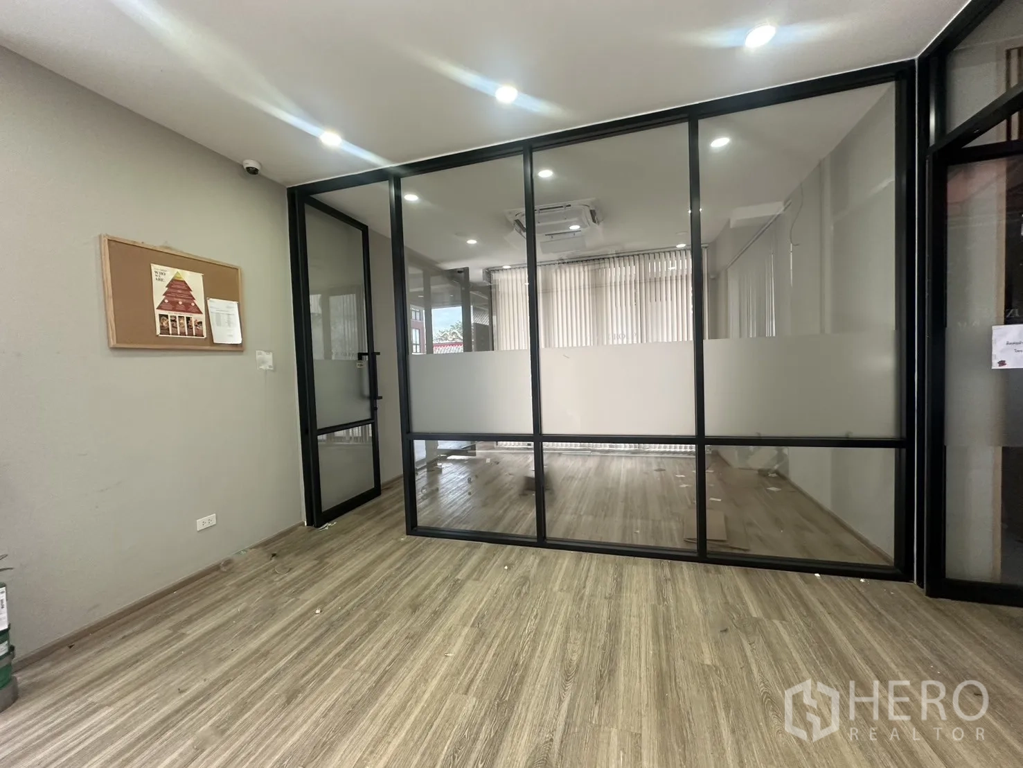 Home Office for rent in Pathum Wan, Bangkok - Reception or meeting area divided by glass partitions with wood-look flooring and recessed lights.