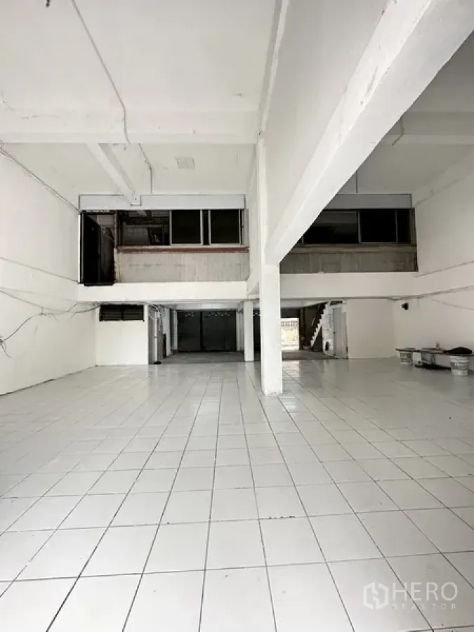 Shophouse for rent or sale in Watthana, Bangkok - Open-plan ground floor with white tiles, high ceiling, and wide frontage.
