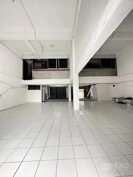 Shophouse for rent or sale in Watthana, Bangkok - Open-plan ground floor with white tiles, high ceiling, and wide frontage.