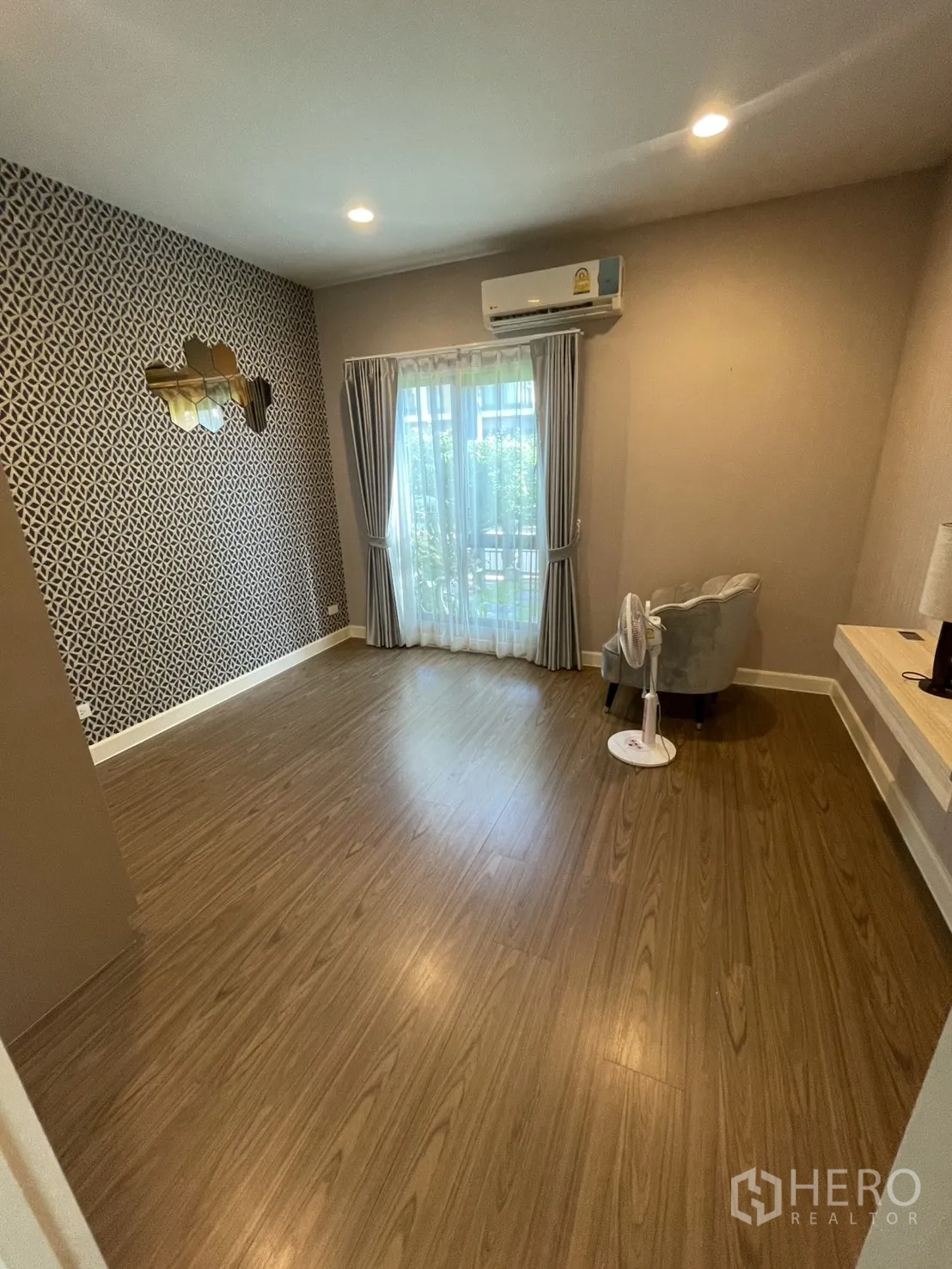 Detached House for rent or sale in Lam Luk Ka, Pathum Thani - Secondary bedroom with accent wall, large window, air-conditioner and warm wood floors.