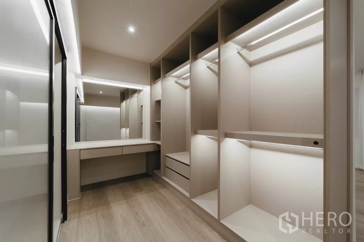Townhouse for rent in Watthana, Bangkok - Dressing room with vanity mirror and illuminated open wardrobes.