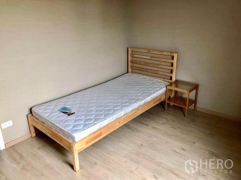 Townhouse for rent in Suan Luang, Bangkok - Minimalist guest bedroom with a single wooden bed, side table and laminate flooring.