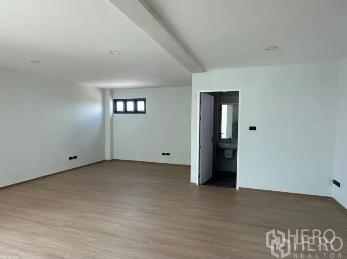 Warehouse for sale in Lam Luk Ka, Pathum Thani - Large office room with wood floors and an en-suite bathroom visible through the open door.