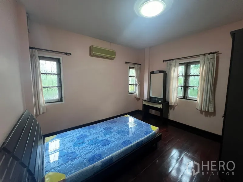 Detached House for rent in Bang Na, Bangkok - Bedroom with windows on two sides, air conditioner and wooden flooring
