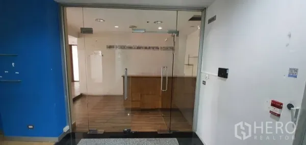 Office Space for rent in Watthana, Bangkok - Glass double-door entrance leading to a reception area with a wooden counter and timber flooring.