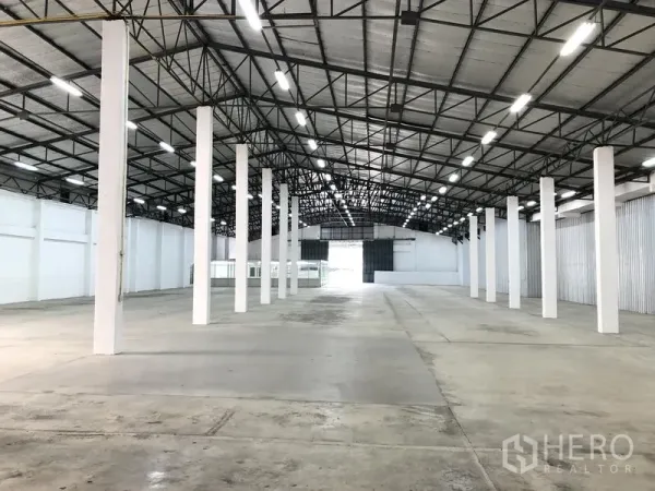 Warehouse for rent in Nonthaburi - Open-plan warehouse view with multiple support columns, high clearance and a rear loading door.
