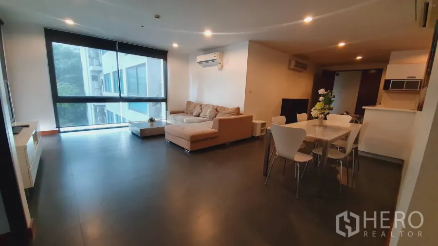 Condominium for rent in Khlong Toei, Bangkok - Spacious open-plan living and dining room with sofa, dining table and air-conditioning.