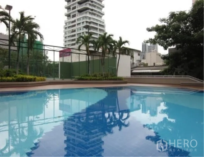Condominium for rent in Watthana, Bangkok - Outdoor swimming pool with palm trees and city views at a Watthana Bangkok condominium.