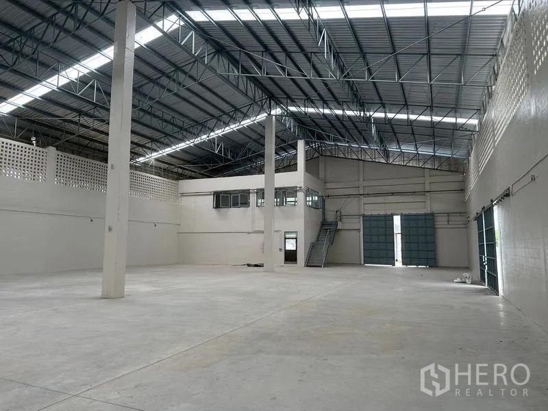 Factory for rent in Lam Luk Ka, Pathum Thani - Wide factory floor with mezzanine office, stair access and tall rolling doors.