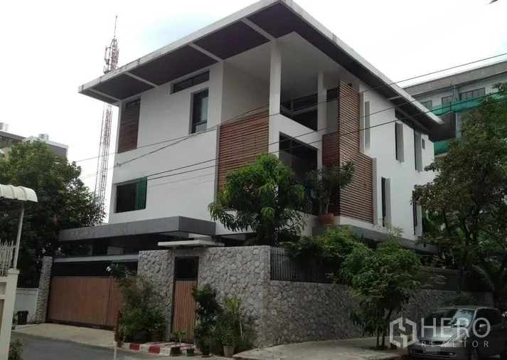 Home Office for rent or sale in Bang Rak, Bangkok - Modern three-storey home office exterior with stone wall, wood accents and trees in Silom.