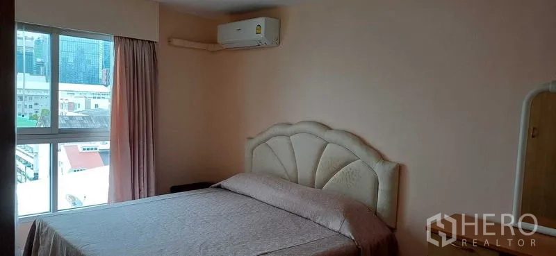 Condominium for sale in Pathum Wan, Bangkok - Master bedroom with upholstered headboard, wall-mounted air conditioner and window with skyline views.