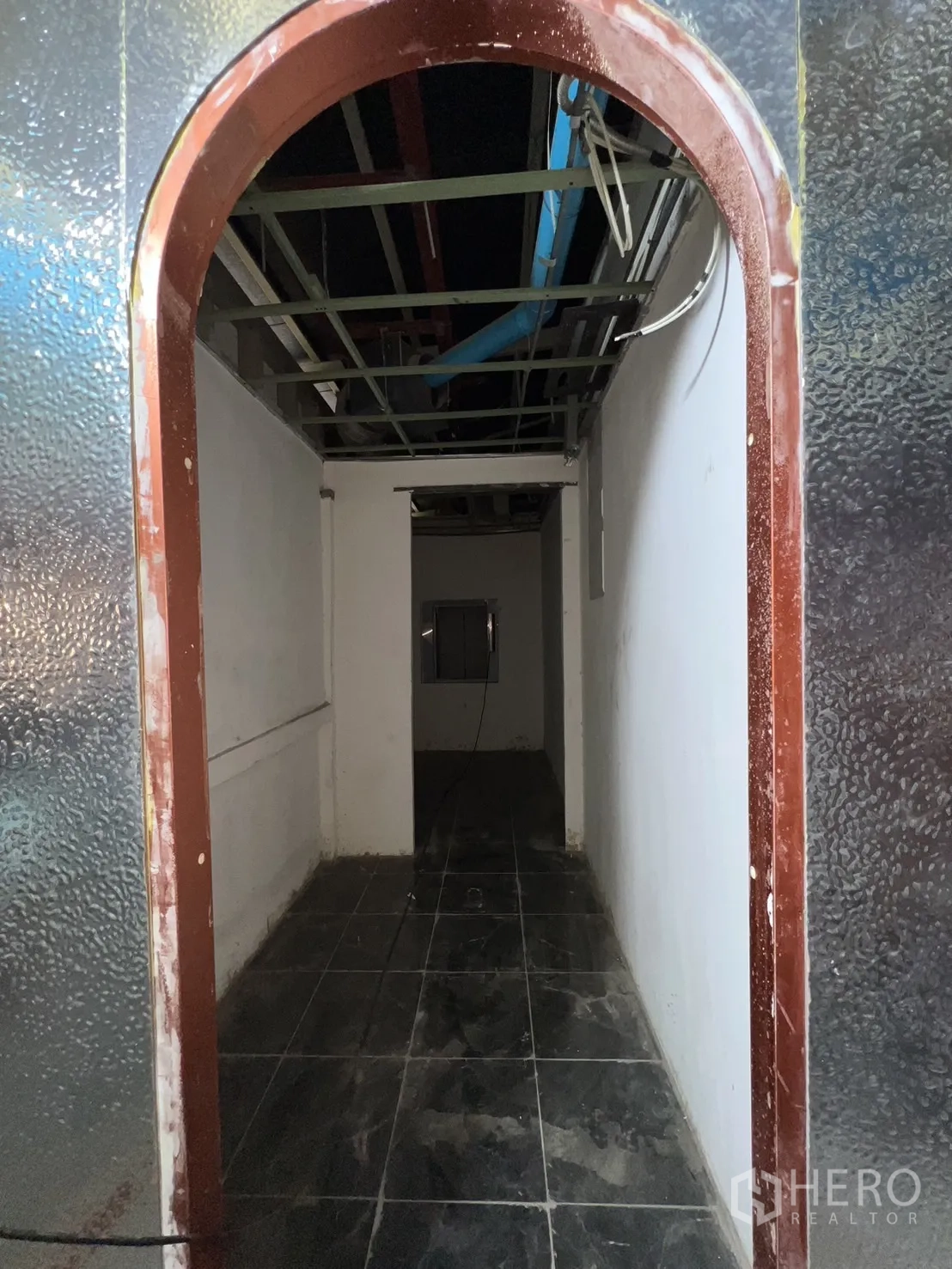 店屋 出租 - 未完成走廊，黑色地砖与裸露天花管线。