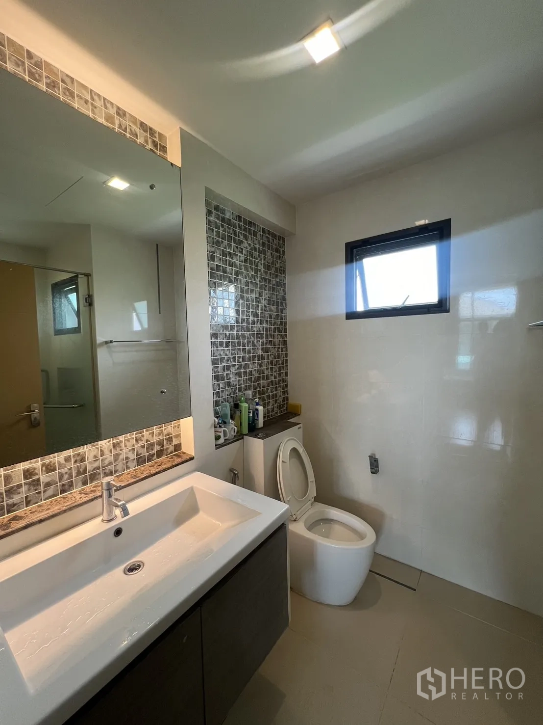 Detached House for rent in Bang Kapi, Bangkok - Bathroom with long vanity, mosaic accent strip, and toilet.