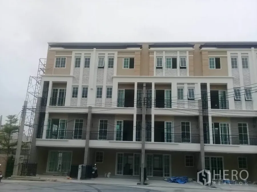 Home Office for rent in Bang Na, Bangkok - Four-storey modern home office facade with balconies and tall windows in a gated Bang Na project.