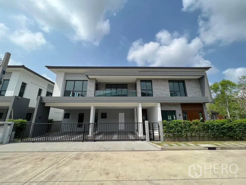 Detached House for rent - Modern two-storey detached house facade with gated double parking and balcony under blue sky.