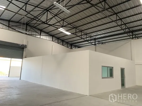 Warehouse for rent in Samut Prakan - Warehouse bay with internal office block, high roof structure and roller shutter access.