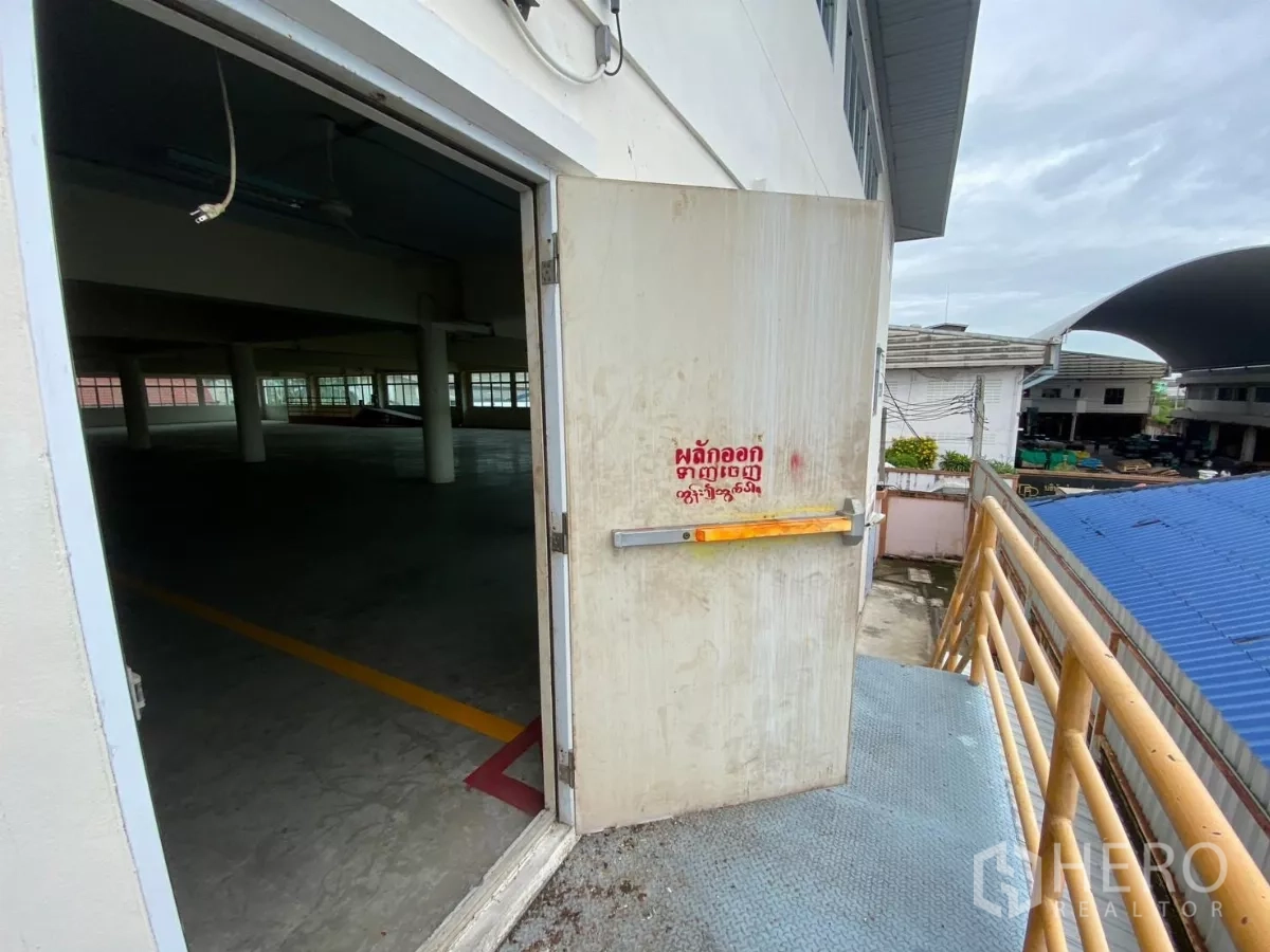 Factory for rent in Khlong Toei, Bangkok - Emergency exit door opening to an upper-level production floor and balcony walkway.