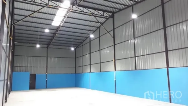 Factory for rent in Khlong Luang, Pathum Thani - Factory interior showing high clear-span steel roof, skylight panels, bright LED lighting and smooth concrete floor.