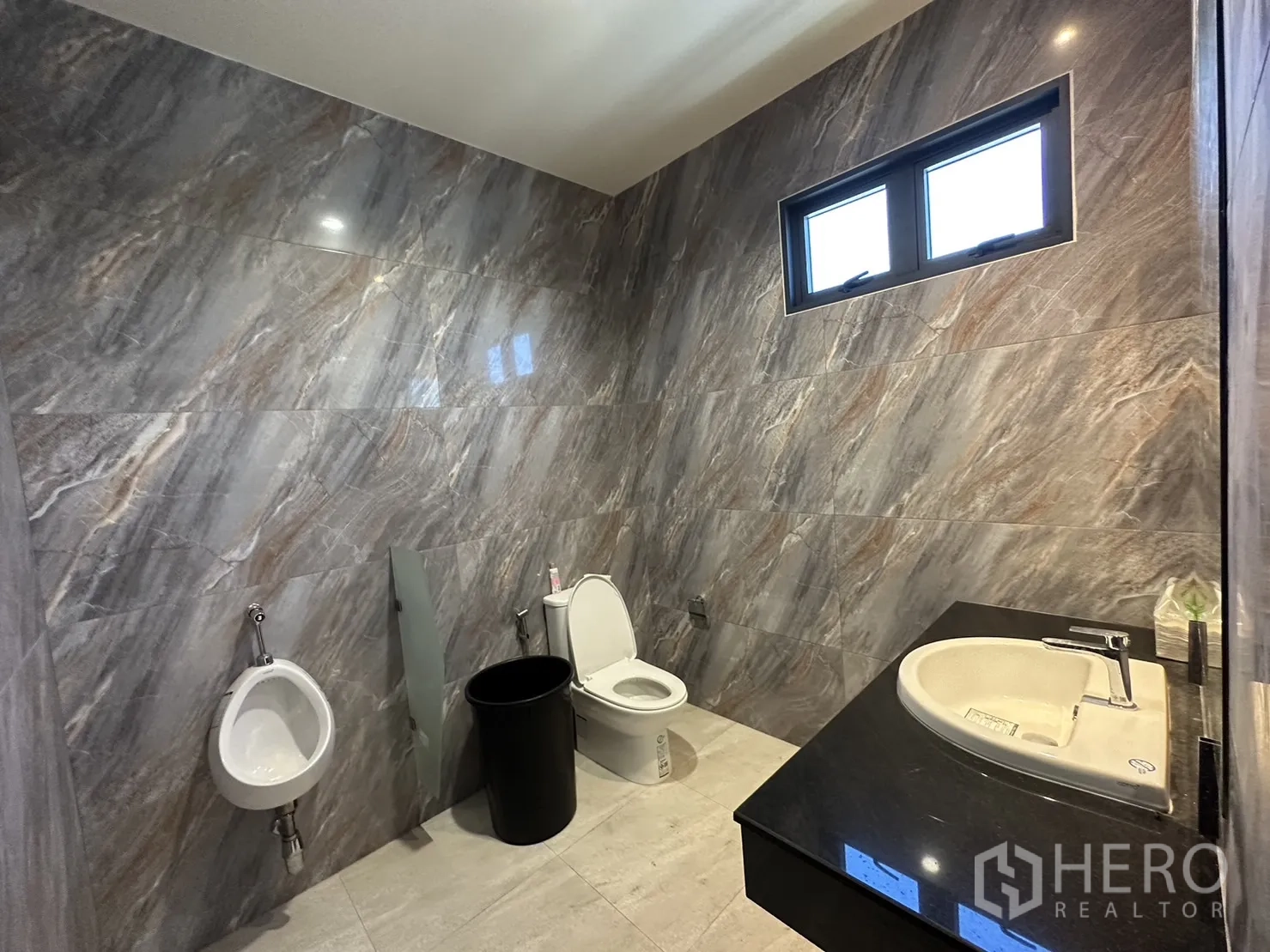 Factory for sale in Lam Luk Ka, Pathum Thani - Tiled restroom with urinal, toilet, and countertop basin.