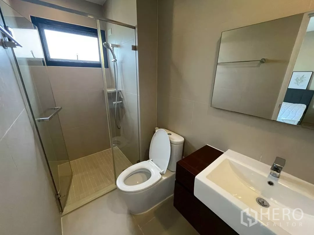 Townhouse for rent in Suan Luang, Bangkok - Third bathroom with glass shower enclosure, vanity cabinet and neutral tiles.