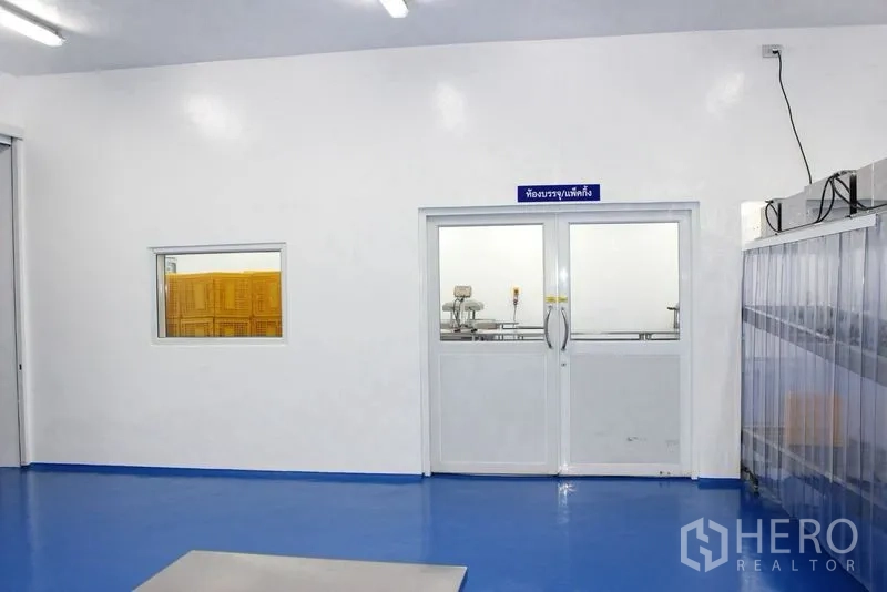 Factory for rent or sale in Krathum Baen, Samut Sakhon - Interior corridor with double glass doors and a viewing window into a processing room.