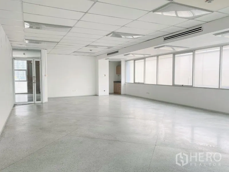 Office Space for rent in Chatuchak, Bangkok - Spacious office interior with glass entry door, long window wall, ducted air vents and pantry alcove.