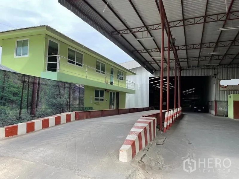 Warehouse for sale in Lam Luk Ka, Pathum Thani - Raised loading ramp leading to the main warehouse entrance beside a two-story office block.