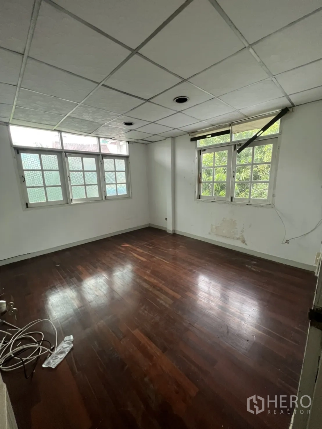 Detached House for rent or sale in Sathon, Bangkok - Unfurnished bedroom with wood floors and twin windows overlooking greenery.