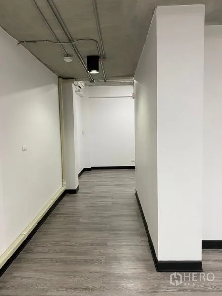 Office Space for rent - Long corridor inside the office showing grey laminate floors and visible ceiling piping for a contemporary look.