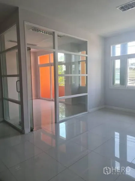 Factory for rent or sale in Lam Luk Ka, Pathum Thani - Glass-partitioned office room with sliding door and orange accent wall visible outside.
