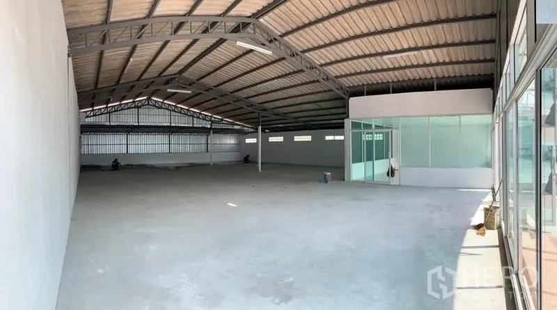 Warehouse for rent in Mueang Pathum Thani, Pathum Thani - Panoramic view of open-plan warehouse showing glass-partitioned office and bright skylit space.