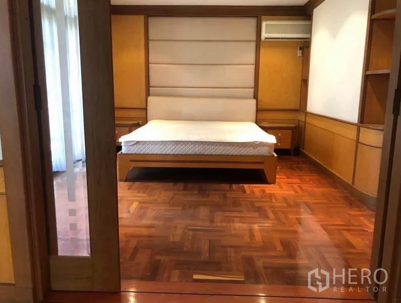 Detached House for sale in Mueang Samut Prakan, Samut Prakan - Bedroom with built-in headboard, wood flooring and sliding door access.