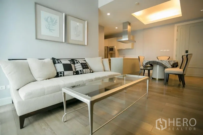 Condominium for rent or sale in Pathum Wan, Bangkok - Stylish lounge with sofa, framed artwork and open-plan kitchen-dining layout.