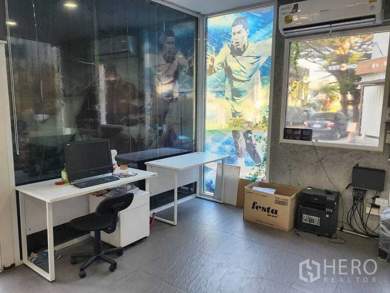 Warehouse for rent in Lat Phrao, Bangkok - Air-conditioned office room with desks, computer, large windows and sports graphic decals.