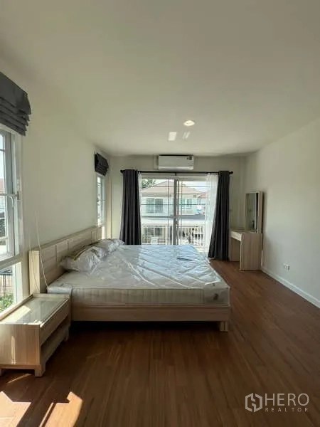 Detached House for rent in Bang Kapi, Bangkok - Spacious master bedroom with sliding doors to a balcony and wood flooring.